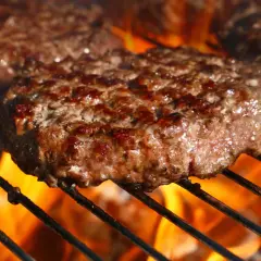 Soczyste kotlety na burgery grillujące się nad płomieniami.