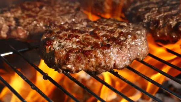 Soczyste kotlety na burgery grillujące się nad płomieniami.